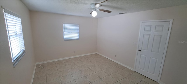 spare room featuring light tile floors, ceiling fan, and a healthy amount of sunlight