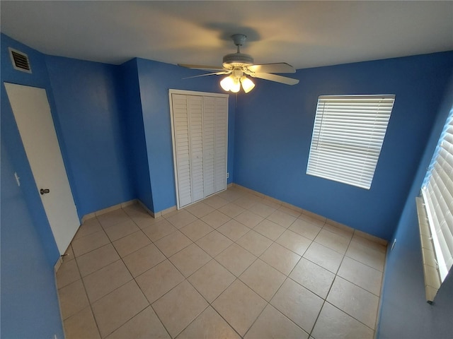 tiled spare room featuring ceiling fan