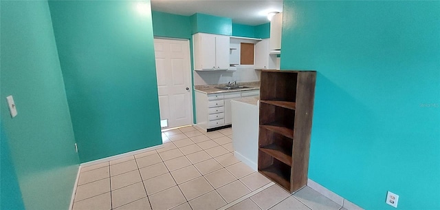 kitchen featuring sink, white cabinets, and light tile flooring