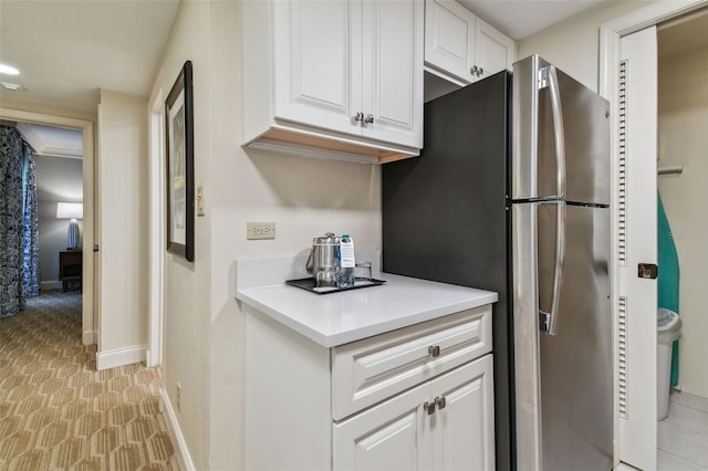 kitchen featuring stainless steel fridge, white cabinets, and light tile floors