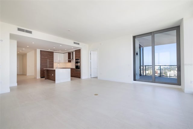 unfurnished living room featuring light tile flooring and sink