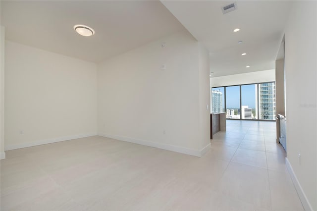 tiled empty room featuring floor to ceiling windows