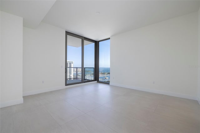 spare room featuring a wall of windows and light tile floors