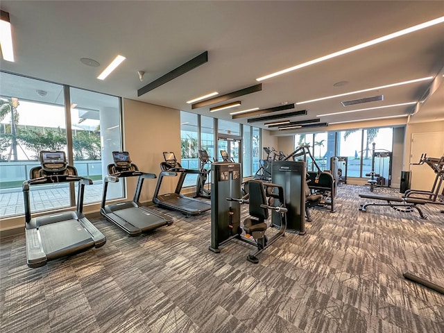 workout area with plenty of natural light, expansive windows, and dark colored carpet