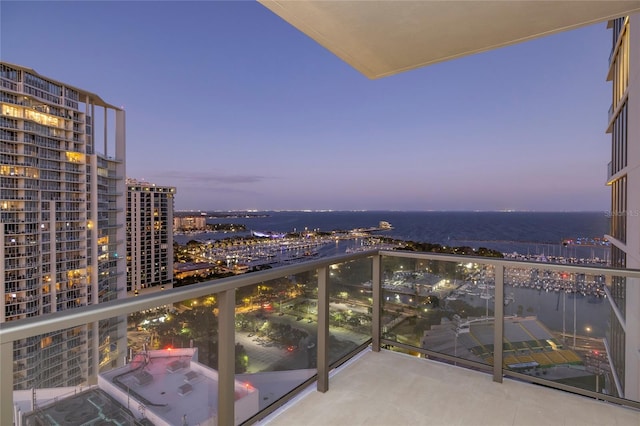 balcony at dusk featuring a water view