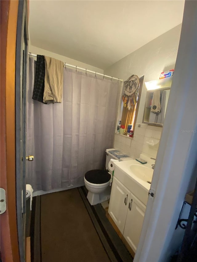 bathroom featuring tile walls, tasteful backsplash, toilet, and vanity