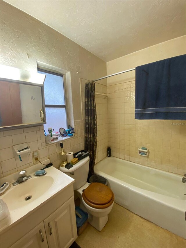 full bathroom with tile walls, tasteful backsplash, toilet, shower / bath combo with shower curtain, and oversized vanity