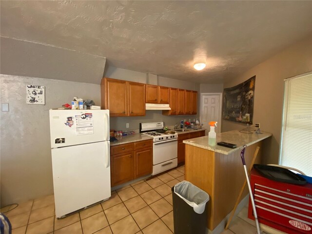 kitchen featuring light stone counters, light tile floors, kitchen peninsula, white appliances, and sink