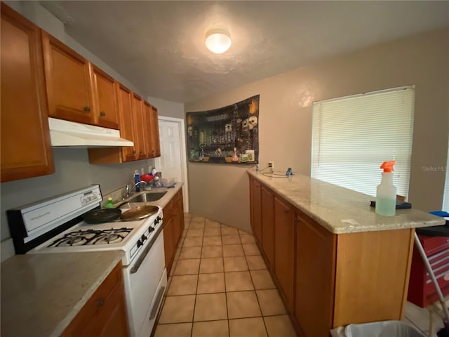 kitchen with light tile floors, light stone countertops, kitchen peninsula, gas range gas stove, and sink