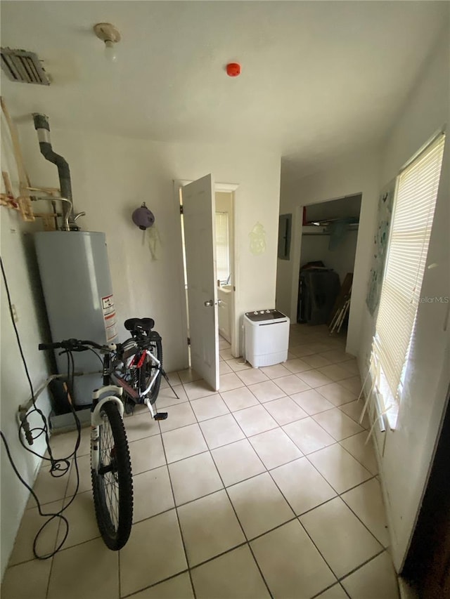 hall featuring light tile flooring and water heater