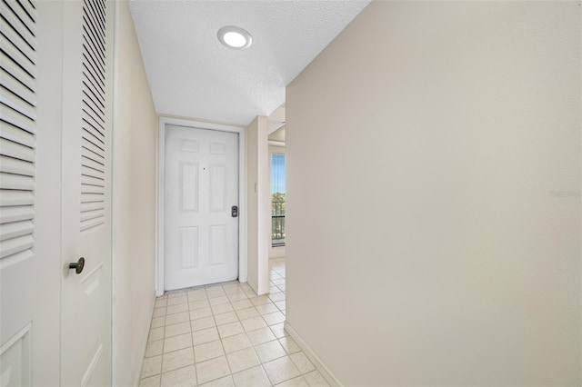 corridor with a textured ceiling and light tile flooring