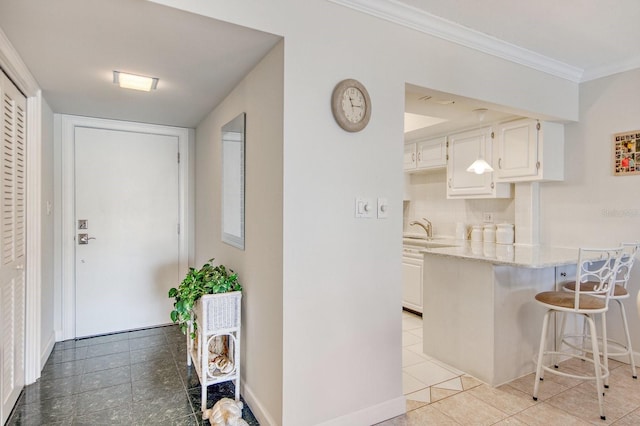 kitchen featuring ornamental molding, light stone countertops, sink, and white cabinets