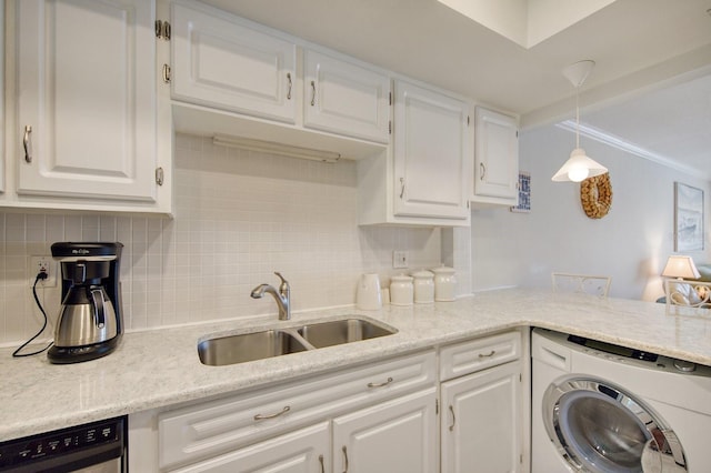 kitchen with washer / clothes dryer, white cabinetry, hanging light fixtures, and sink