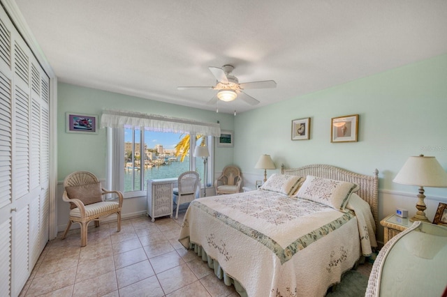 tiled bedroom featuring a water view, ceiling fan, and a closet