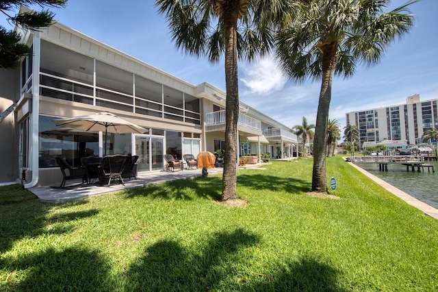 back of property featuring a water view, a sunroom, and a lawn