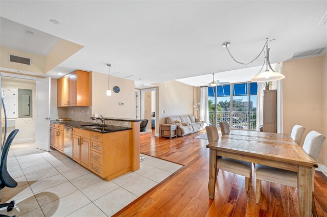 interior space with ceiling fan, light tile floors, hanging light fixtures, dishwasher, and tasteful backsplash