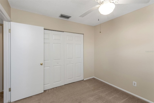 unfurnished bedroom with carpet flooring, a textured ceiling, ceiling fan, and a closet