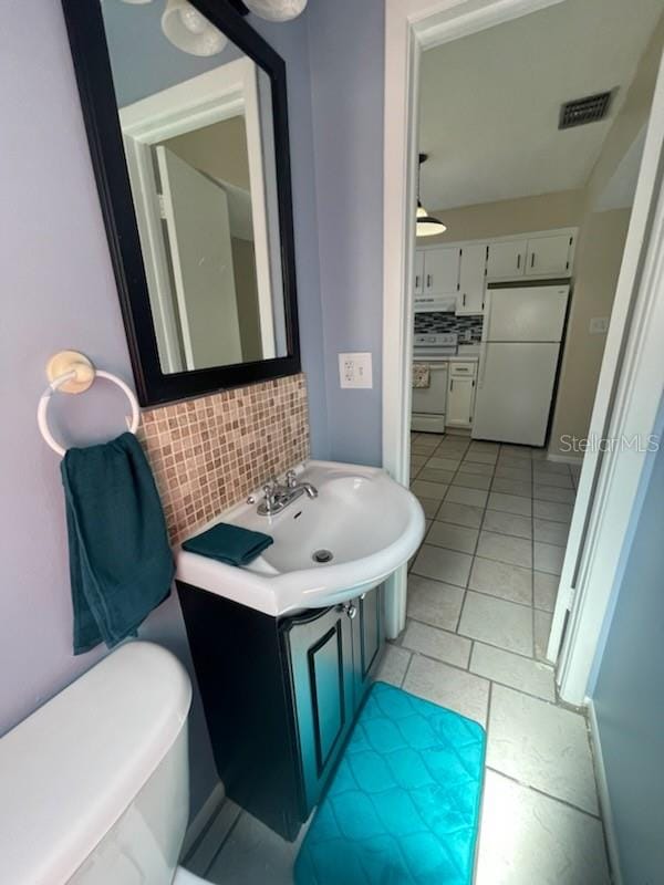 bathroom featuring tile patterned flooring, backsplash, sink, and toilet