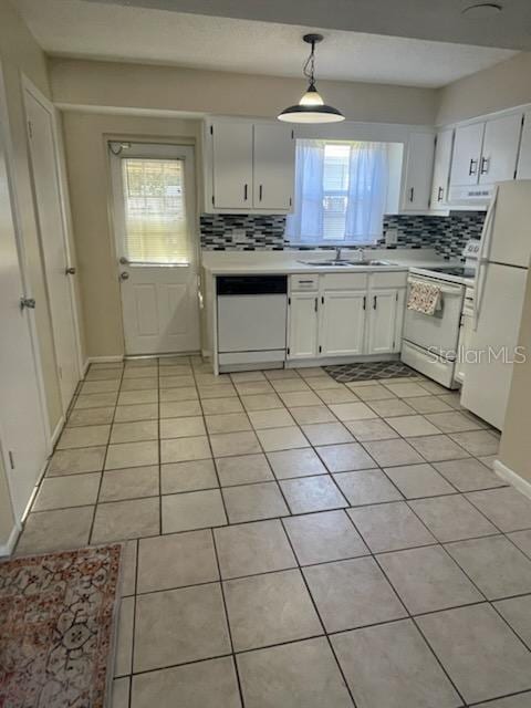 kitchen featuring sink, white appliances, light tile patterned floors, white cabinetry, and hanging light fixtures