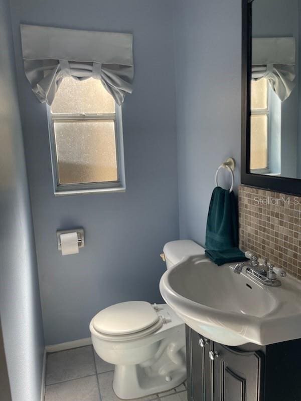 bathroom featuring plenty of natural light, toilet, vanity, and backsplash