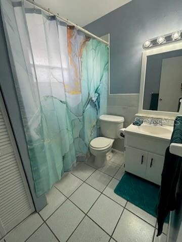 bathroom with tile patterned flooring, tile walls, a shower with shower curtain, vanity, and toilet