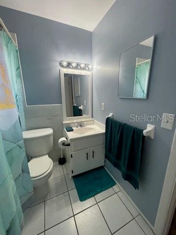 bathroom with vanity, toilet, tile patterned flooring, and tile walls