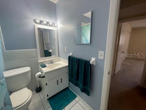 bathroom featuring vanity, tile walls, tile patterned floors, and toilet