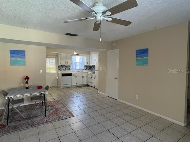 kitchen with tasteful backsplash, white cabinetry, light tile patterned floors, white appliances, and a textured ceiling