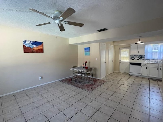 unfurnished dining area featuring ceiling fan, a textured ceiling, and light tile patterned floors