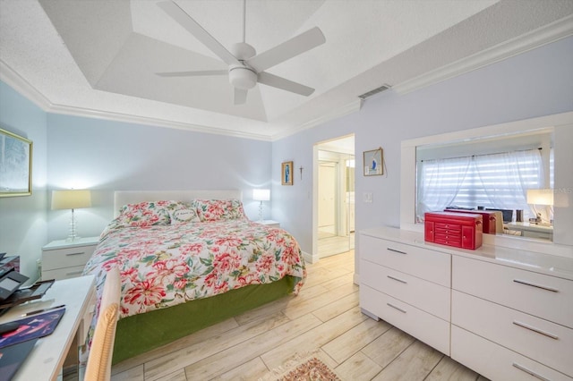 bedroom with ceiling fan, crown molding, light hardwood / wood-style floors, and a raised ceiling