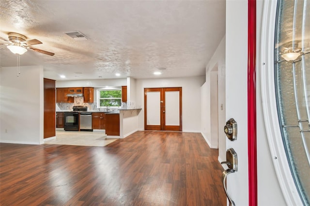 kitchen featuring black / electric stove, stainless steel dishwasher, a textured ceiling, and hardwood / wood-style flooring