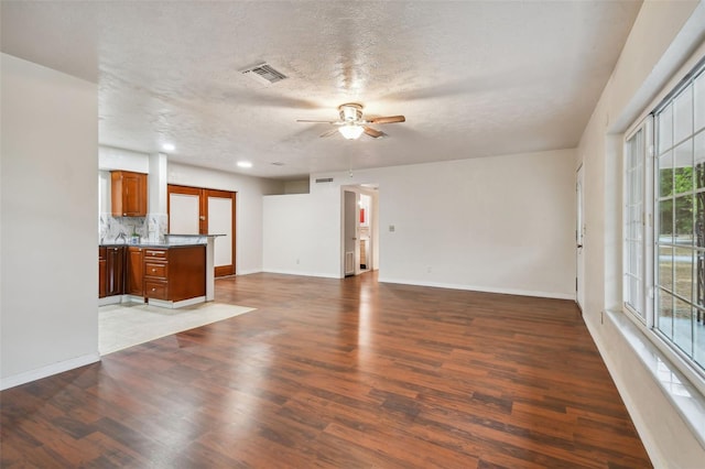 unfurnished living room with ceiling fan, dark hardwood / wood-style flooring, and a textured ceiling