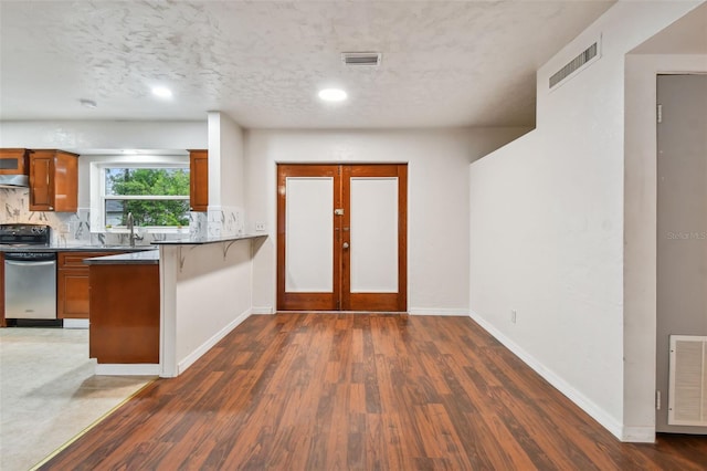 kitchen with dishwasher, sink, decorative backsplash, a textured ceiling, and dark hardwood / wood-style flooring