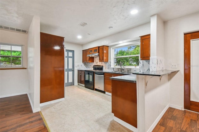 kitchen with appliances with stainless steel finishes, light hardwood / wood-style floors, a kitchen breakfast bar, and sink