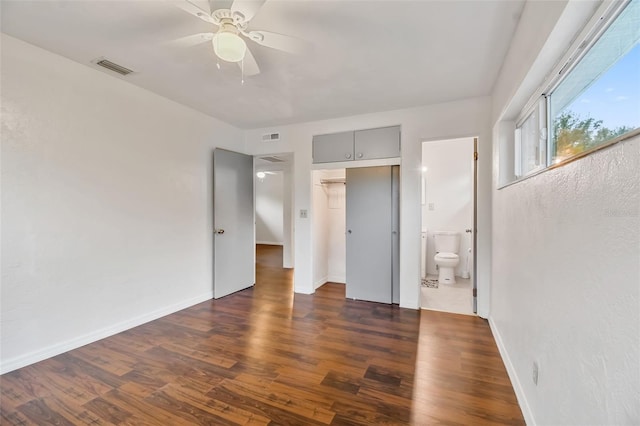 unfurnished bedroom featuring ensuite bathroom, dark hardwood / wood-style flooring, and ceiling fan