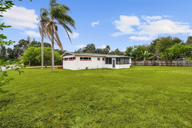 rear view of property featuring a sunroom and a yard