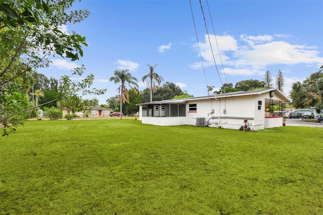 back of property featuring a sunroom, central AC, and a lawn