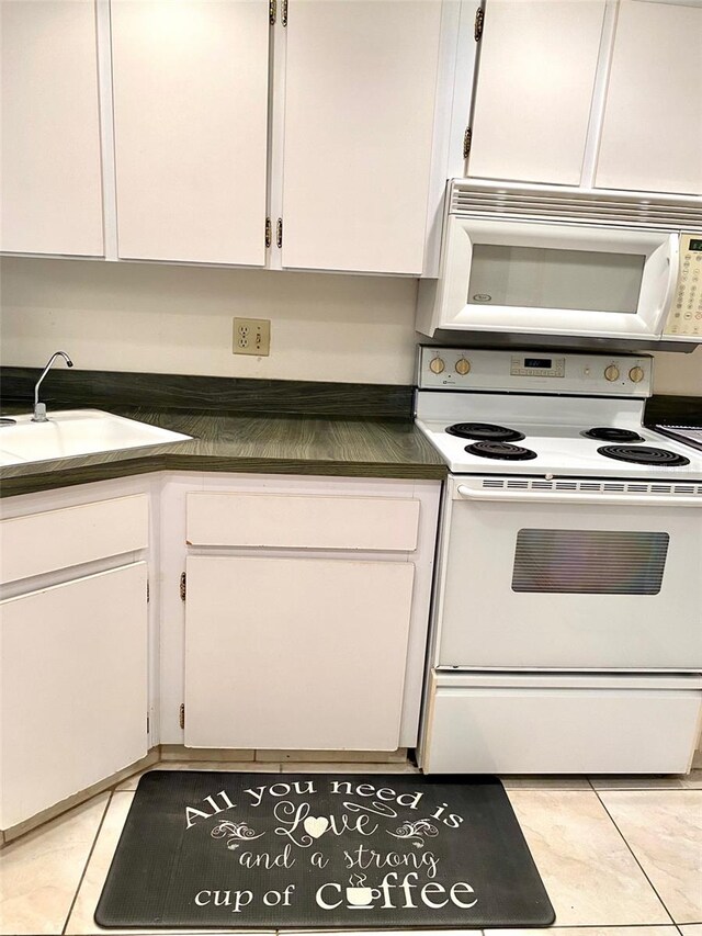 kitchen with white appliances, white cabinets, and a sink