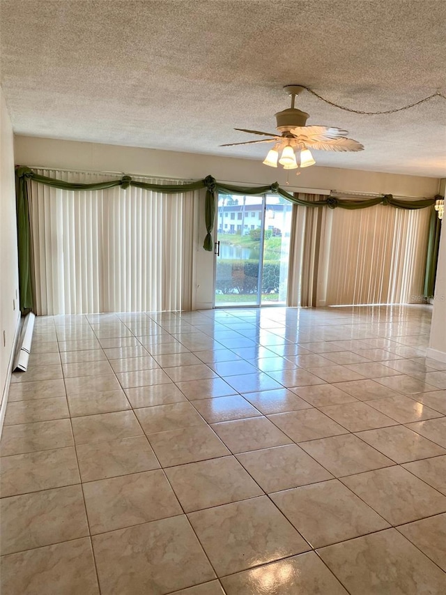 empty room featuring a textured ceiling, ceiling fan, baseboard heating, and light tile patterned flooring