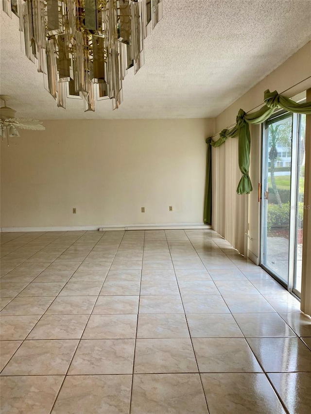 spare room featuring a textured ceiling, ceiling fan, light tile patterned flooring, and baseboards