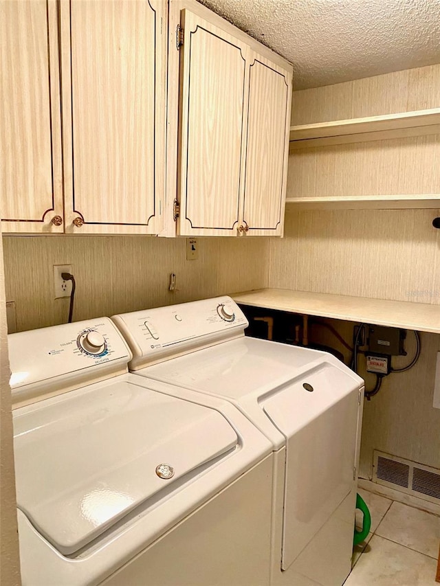 laundry area featuring tile patterned flooring, visible vents, cabinet space, and washing machine and clothes dryer