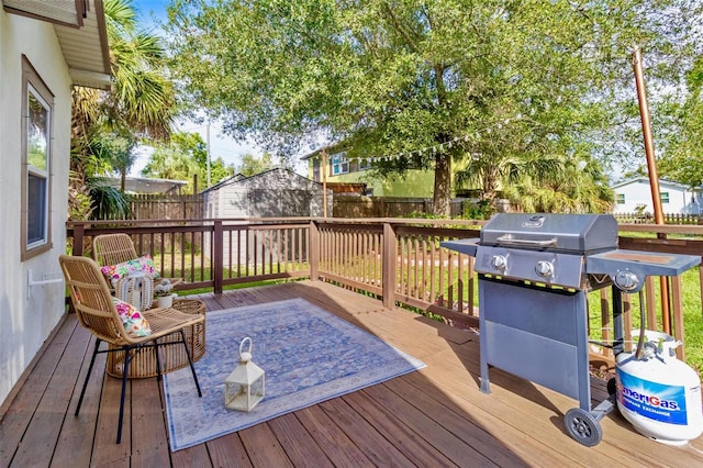 wooden deck featuring a storage shed, a fenced backyard, and an outbuilding