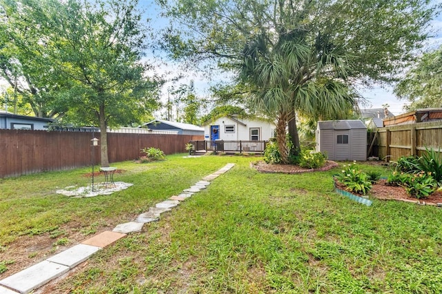 view of yard featuring a fenced backyard, an outdoor structure, a wooden deck, and a shed