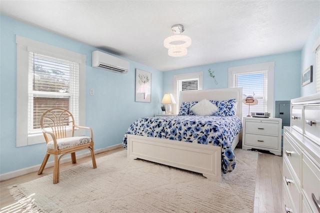 bedroom with light wood-style flooring, baseboards, and a wall mounted air conditioner