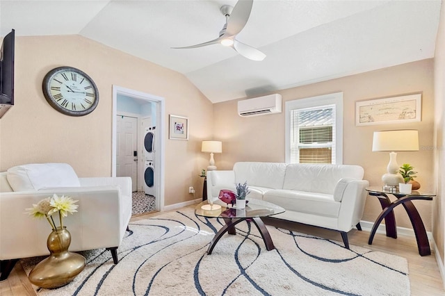 living area with a ceiling fan, lofted ceiling, stacked washer / drying machine, light wood-style floors, and a wall mounted AC