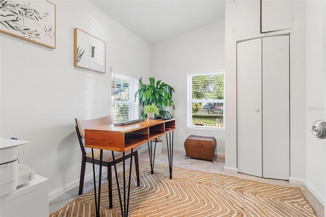 home office with lofted ceiling, light carpet, a wealth of natural light, and baseboards