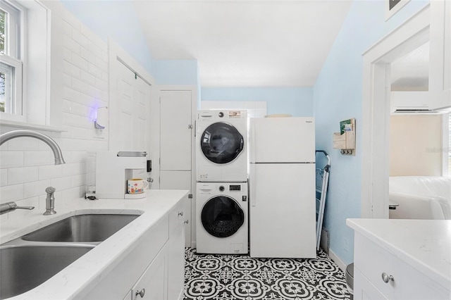 clothes washing area with light tile patterned floors, laundry area, stacked washer / dryer, and a sink