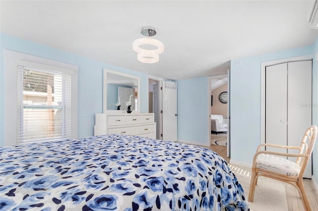 bedroom with light wood-type flooring, ensuite bath, and baseboards