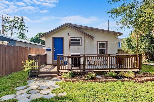 back of house with fence, a wooden deck, and stucco siding