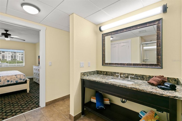 bathroom with a paneled ceiling, tile patterned floors, vanity, a shower with door, and ceiling fan